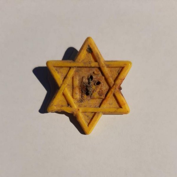 01 -  Žltý plastový odznak v tvare židovskej šesťcípej hviezdy s reliéfom písmen HŽ („hospodársky [dôležitý] Žid“), nájdený pri archeologickom výskume Hlavného námestia v Bratislave, líce. Foto: Petra Kmeťová