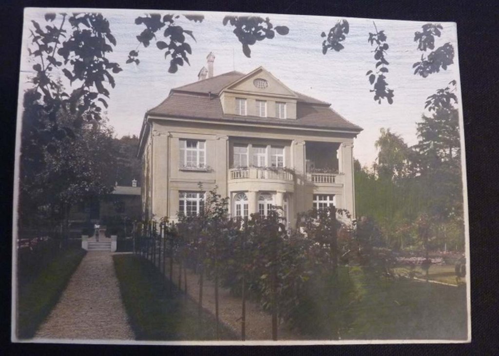 Kolorovaná fotografia Pavlom FábrymfarbičkamiCarand’Ache z júla 1927. Na fotografii vidieť bohato komponovaný nástupný priestor vily s mnohopočetnými výsadbami ruží. Po ľavej strane vily vidieť terasovito upravený priestor záhrady so schodiskom. Na ľavo od hlavného parteru je zopakovaná líniová výsadba ruží na kmienkoch. Zdroj: fabryfamily.com