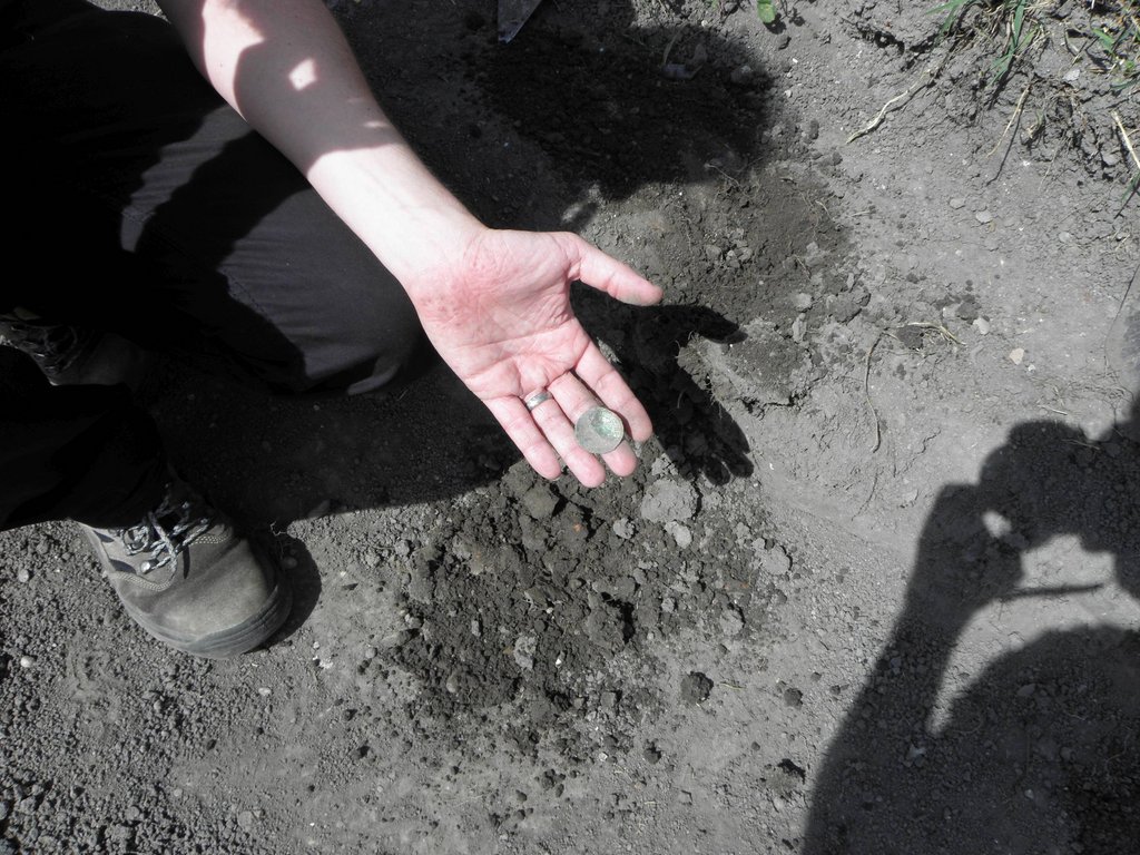 Vyzdvihnutá minca z výkopu pre bazén počas archeologického výskumu miesta nálezu, zdroj: KPÚ Trnava, foto: M. Sládok Vyzdvihnutá minca z výkopu pre bazén počas archeologického výskumu miesta nálezu, zdroj: KPÚ Trnava, foto: M. Sládok